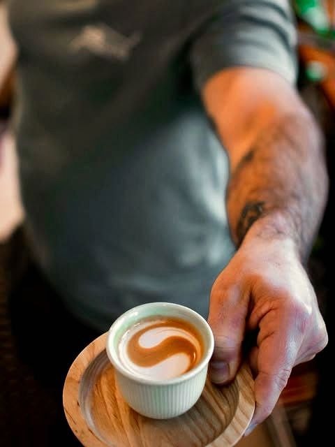 A Homeland barista handing over a fresh espresso